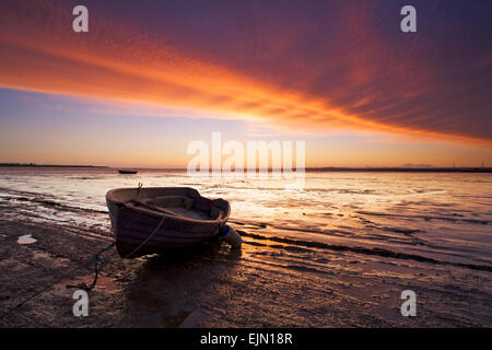 Harty Ferry, Kent, UK. 30 mars 2015. Météo France : une superbe lueur rouge comme une bande de nuages en rouleau juste avant le lever du soleil sur un bateau à rames à l'ancien Harty Ferry Crossing sur la rive de l'estuaire de Swale près de Oare, dans le Kent. Soleil et gratuites va dominer le début du printemps météo pour les prochains jours Banque D'Images