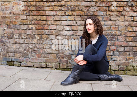 Jeune femme assise sur le trottoir Banque D'Images