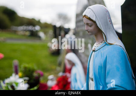 Statue de la Vierge Marie à gauche sur une tombe, avec d'autres statues et objets en arrière-plan Banque D'Images