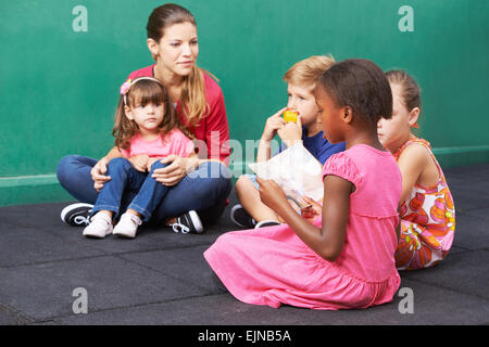 Jeune fille africaine de la lecture à haute voix pour groupe d'enfants dans un jardin d'enfants Banque D'Images