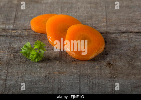 Pour la cuisson des carottes en tranches sur une planche à découper et le persil sur un fond de bois Banque D'Images