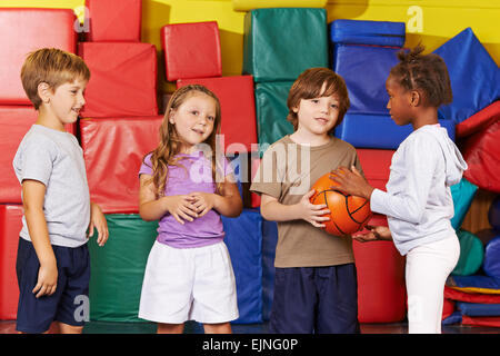 Enfants jouant avec une balle dans la salle de sport de l'école maternelle Banque D'Images