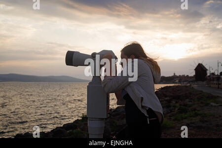 Une femme à l'aide de binoculaires mer travaillant avec des crédits dans le contexte d'un paysage de la mer en début de matinée. Lever du soleil dans les ba Banque D'Images