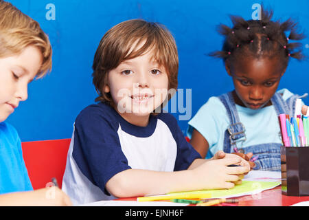 Image peinture enfant sur la table à la maternelle ensemble avec d'autres enfants Banque D'Images