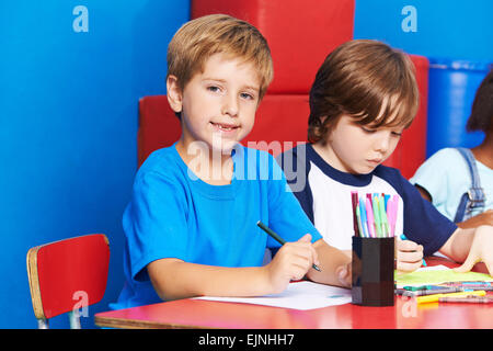 Heureux l'enfant peinture avec feutre en maternelle sur une table Banque D'Images