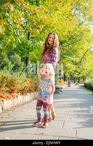 Portrait of happy mother and baby girl walking in city park Banque D'Images