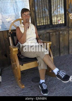 Senior female bénéficiant d'une glace tout en se reposant dans une chaise à bascule en bois Banque D'Images