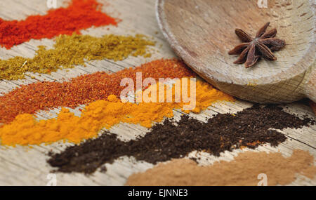Bandes de différentes épices en poudre et une cuillère à l'anis sur fond de bois Banque D'Images