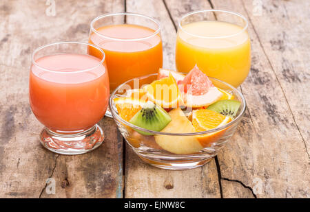 Salade de fruits frais avec divers jus sur table en bois. Arrière-plan de vitamines Banque D'Images