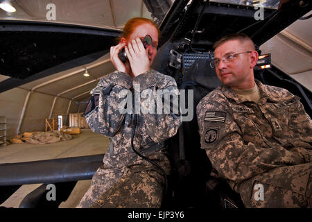 Camp Taji, Iraq, Aug 10, 2009- tout en passant par différents composants d'une AH-64D'hélicoptère d'attaque Apache, 1er lieutenant Carolyn Wagnild gauche, de Boise, Idaho, un pilote d'Apache dans l'entreprise C, 1er Bataillon, 227e Régiment d'aviation, 1st Air Cavalry Brigade, Division de cavalerie, explique comment le système de visée de l'Apache fonctionne au Sgt.1re classe Jonathan Duffey, à Troy (Ohio), le centre des opérations tactiques militaires officier responsable pour la 2e bataillon du 107e régiment de cavalerie de la Garde nationale de l'Ohio. La réunion entre les deux unités est destiné à bâtir la confiance et la compréhension entre e Banque D'Images