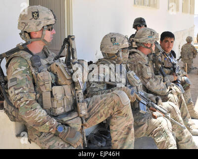 Avec les soldats du 2e Bataillon, 23e Régiment d'infanterie le long des frontières avec la police en uniforme et prendre une pause assis tout en assurant la sécurité pendant un programme afghan de paix et de réconciliation dans la province de Kandahar, Afghanistan. Le s.. Shane Hamann. Banque D'Images