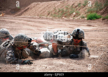 Soldats de la 2e Brigade d'aider et de conseiller, 1re Division d'infanterie, Division des États-Unis - Centre naviguer sous les barbelés pendant la litière-faire obstacle au cours de la meilleure brigade Concours infirmier 19 juin 2011 au camp de la liberté, de l'Iraq. Les équipes représentant des bataillons de autour de la brigade a participé à la compétition, conçus pour imiter l'armée sur le terrain par les experts de l'insigne médical bien sûr. Slt Carolyne Hall, 2e Aab, 1er Inf. Div., USD-C Banque D'Images