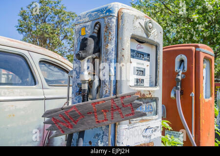 Un 1947 Chrysler Berline 4 portes peinture antirouille avec disparu se trouve garé en face de deux anciennes pompes à essence d'une station de charge. Banque D'Images