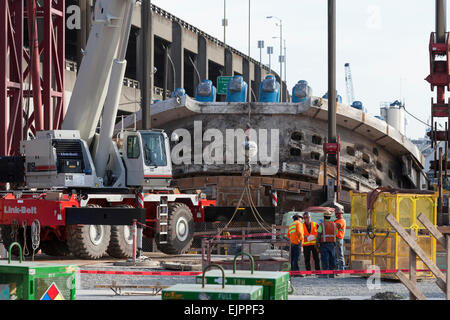 Seattle, Washington, USA. 30Th Mar, 2015. Crane lève le visage de coupe le plus grand tunnel-aléseuse de la surface de réparation - le 30 mars 2015. Le tunnelier, surnommé Bertha, a été retardé depuis décembre 2013 après une surchauffe en raison des dommages causés à l'entraînement de la tête de coupe, les roulements et les joints. Ce retard a duré plus d'un an, car les travailleurs qui ont creusé un puits vertical de 120 pieds vers le bas la tête de coupe pour la réparer. Creuser devrait reprendre en août, une fois les réparations terminées. Crédit : Paul Gordon/Alamy Live News Banque D'Images