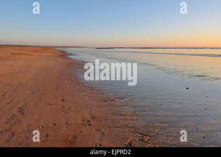 Coucher du soleil sur le sable humide à marée basse avec pied sprint Banque D'Images