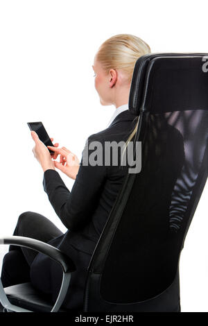 Smiling businesswoman blond assis sur une chaise avec un téléphone mobile Banque D'Images