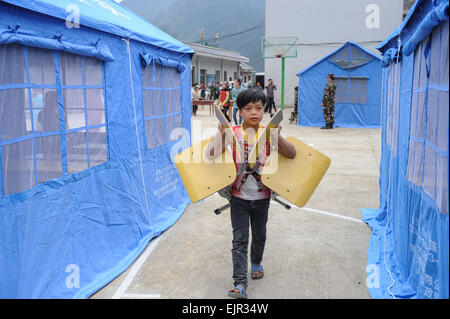 Jianhe, province du Guizhou en Chine. Mar 31, 2015. Un enfant porte des chaises pour l'école de fortune à Xinliu Village de Jianhe, comté de la province du Guizhou, au sud-ouest de la Chine, 31 mars 2015. Les gens de la région ont commencé la reconstruction post-catastrophe le deuxième jour après un séisme de magnitude 5,5 a frappé le comté de Jianhe lundi. Credit : Ou Dongqu/Xinhua/Alamy Live News Banque D'Images