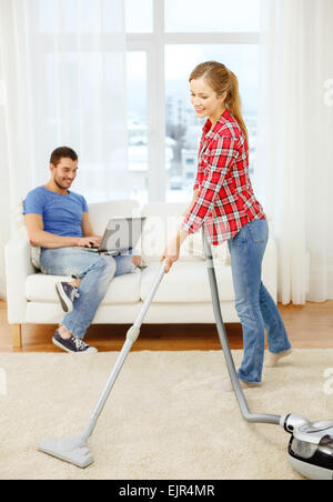 Femme souriante avec Hoover et man with laptop Banque D'Images