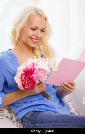 Femme souriante avec carte et bouquet de fleurs Banque D'Images