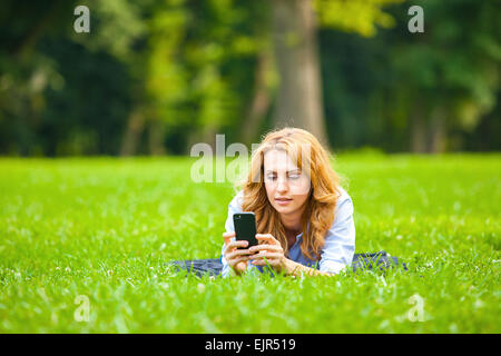 Young blonde woman relaxing in park on Green grass Banque D'Images