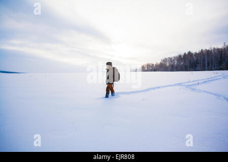 Mixed Race man walking in snowy field Banque D'Images