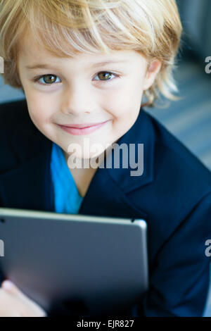 Smiling Caucasian boy in costume holding digital tablet Banque D'Images