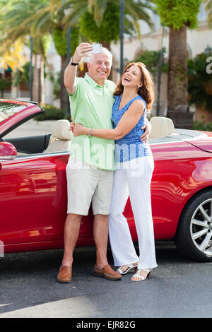 Caucasian couple taking photo téléphone cellulaire près de cabriolet Banque D'Images