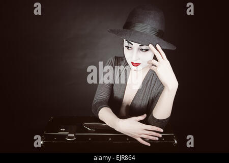 Portrait de femme mime avec une valise sur un fond noir Banque D'Images