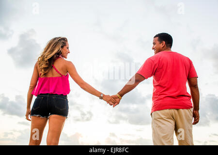 Low angle view of couple holding hands sous ciel nuageux Banque D'Images