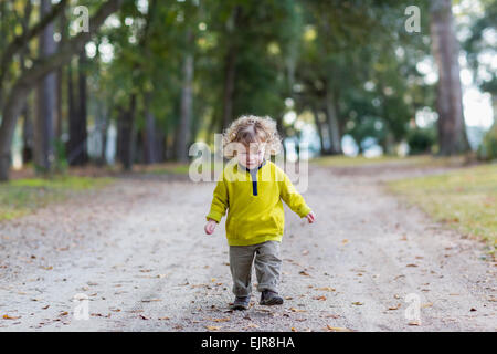 Caucasian baby boy walking on dirt road Banque D'Images