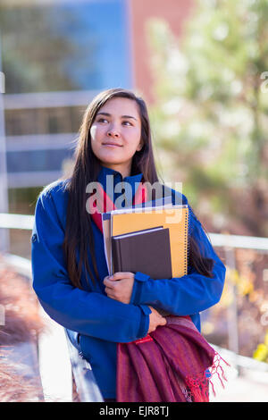 Mixed Race student holding books sur le campus Banque D'Images