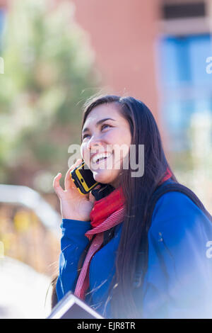 Mixed Race student talking on cell phone on campus Banque D'Images