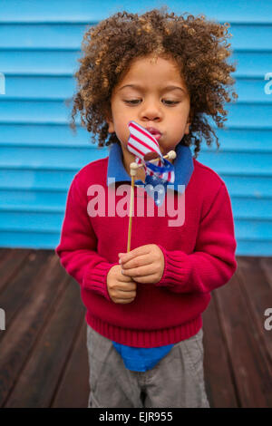 Les Insulaires du Pacifique, boy blowing pinwheel patriotique Banque D'Images