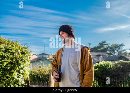 Young man drinking beer in backyard Banque D'Images