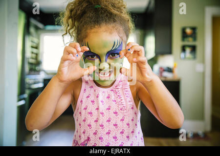 Mixed Race girl grogne avec la peinture pour le visage Banque D'Images