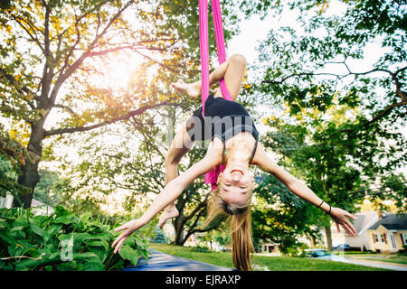 Acrobatic Caucasian girl accroché sur le tissu sous le tree Banque D'Images