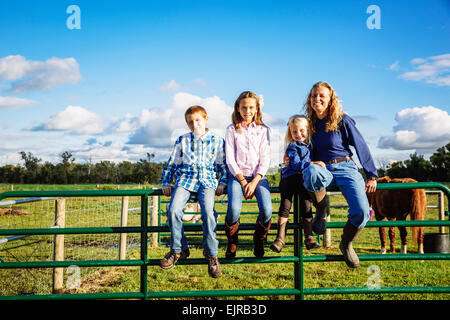 Caucasian farmer et les enfants assis sur clôture sur ranch Banque D'Images