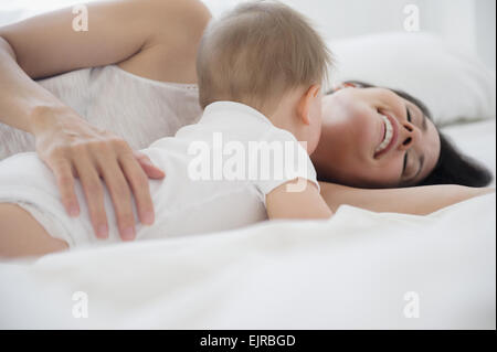 Mixed Race woman with baby on bed Banque D'Images