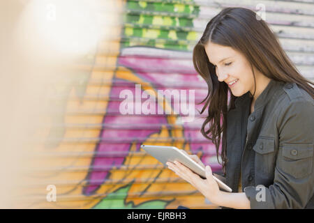 Caucasian woman using digital tablet près de mur de graffiti Banque D'Images