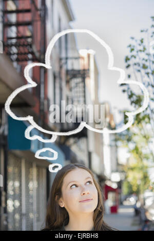 Caucasian woman looking up at bulle pensée Banque D'Images