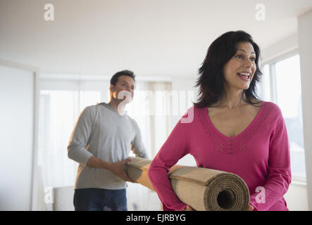 Couple carrying rouleau de tapis dans la salle de séjour Banque D'Images