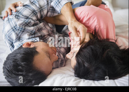 Close up of couple cuddling on bed Banque D'Images