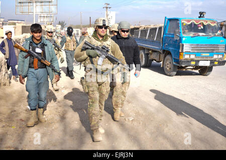 La 1ère Armée américaine, le lieutenant Joseph au milieu, Laurent Rosaz chef de section pour le 1er peloton, Troop P Palehorse, 4e Escadron, la Force opérationnelle combinée Dragoon, retourne à son véhicule avec un membre de la police en uniforme afghane après l'engagement avec les anciens du village le 16 décembre 2013, à la province de Kandahar, Afghanistan. Les deux unités ont effectué une série de missions partenaires à divers postes de contrôle de sécurité de l'ensemble de la province. Le sergent de l'armée américaine. Joshua Edwards Banque D'Images