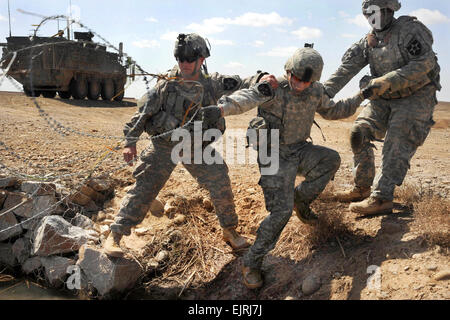 La 1ère Armée américaine, le Lieutenant Brian Faulkner, à gauche, et Sgt. Okuribido Muyiwa, droit, l'aide de la CPS. Louis Phay de tomber dans l'eau lors d'une mission le long de la route 601 dans la province de Helmand, Afghanistan, le 6 mars 2010. Faulkner, Okuribido et Phay, affecté à la Compagnie A, 4e Bataillon, 23e Régiment d'infanterie, mènent des opérations pour augmenter la liberté de mouvement afghan le long des routes. Le s.. Jones Banque D'Images