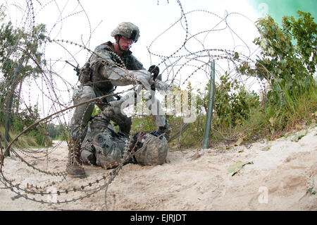 Une équipe d'ingénieurs de combat avec la 82e Division aéroportée, 1ère Brigade Combat Team traverse un fil de fer barbelés lors d'un exercice d'entraînement le 21 juillet 2011, à Fort Bragg, N.C. En dépit des 105 degrés de chaleur, les parachutistes formés tout au long de la journée et dans la nuit. Le Sgt. Michael J. MacLeod Banque D'Images