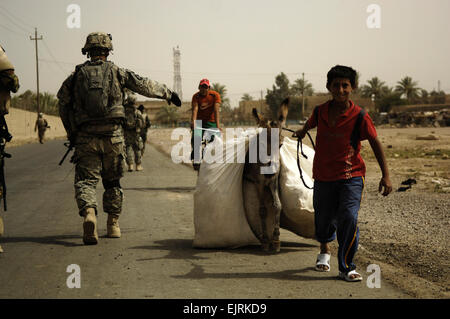 Les citoyens irakiens passent des soldats américains, alors que les soldats retournent à la station commune de sécurité de l'Irak après une Shula, mission conjointe au Shula, l'Iraq le 19 juillet 2008. Les soldats américains font partie du 2e peloton, Compagnie Bravo, 1er bataillon du 502e Régiment d'infanterie, 101ème Division aéroportée. Photo par le sergent. Manuel J. Martinez Banque D'Images