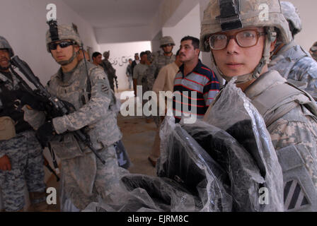 BASE d'opérations avancée, FALCON, l'Iraq - SPC. Christopher McDonald, un fantassin affecté à la Compagnie A, 4e Bataillon, 64e régiment de blindés, est titulaire d'une brassée de sacs à dos au cours d'une distribution de fournitures scolaires le 14 octobre à l'École d'Ishtar dans la communauté du sud de Bagdad Risalah. McDonald, qui est originaire de Hickory, N.C., est attaché à la 1ère Brigade Combat Team, 4e Division d'infanterie, Division Multinationale ñ Bagdad, servant un 15 mois de déploiement dans le cadre de l'opération Iraqi Freedom. Soldats et policiers nationaux à partir de la 5e Brigade, 2e Division NP, distribué des fournitures scolaires à environ Banque D'Images