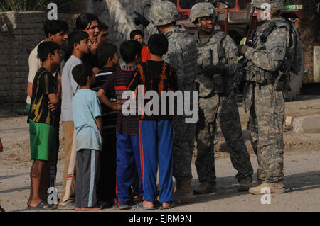 Les soldats du 1er Bataillon, 66e Régiment Blindé, 4 Brigade Combat Team, 10e division de montagne passer des informations fugitives prospectus à des enfants tout en participant à l'opération fer à repasser H1018 dans Muhallah 741, Al Amin, l'est de Bagdad, le 28 octobre, 2008. Banque D'Images