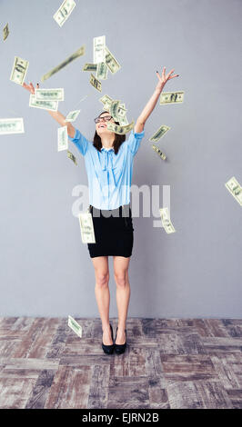 Business Woman standing in the rain du dollar bills à très heureux. Le port en chemise bleue, robe noire et lunettes. Banque D'Images