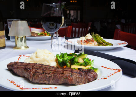 Une plaque blanche est titulaire d'un délicieux steak d'aloyau grillé avec un côté de la purée de pommes de terre et macédoine de légumes frais. Banque D'Images